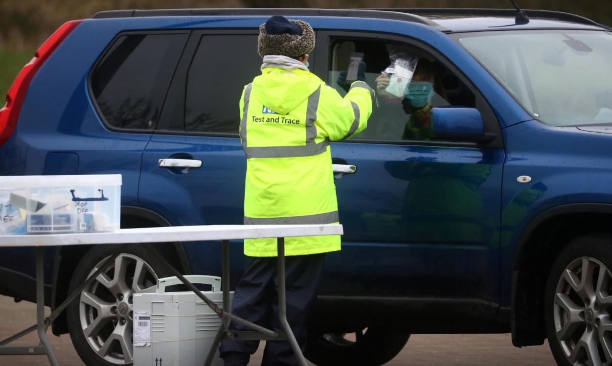 A worker collects a swab from a car window at a test centre in Goldsworth Park, as the South African variant of the novel coronavirus is reported in parts of Surrey, in Woking, Britain, February 1, 2021. - Avaz