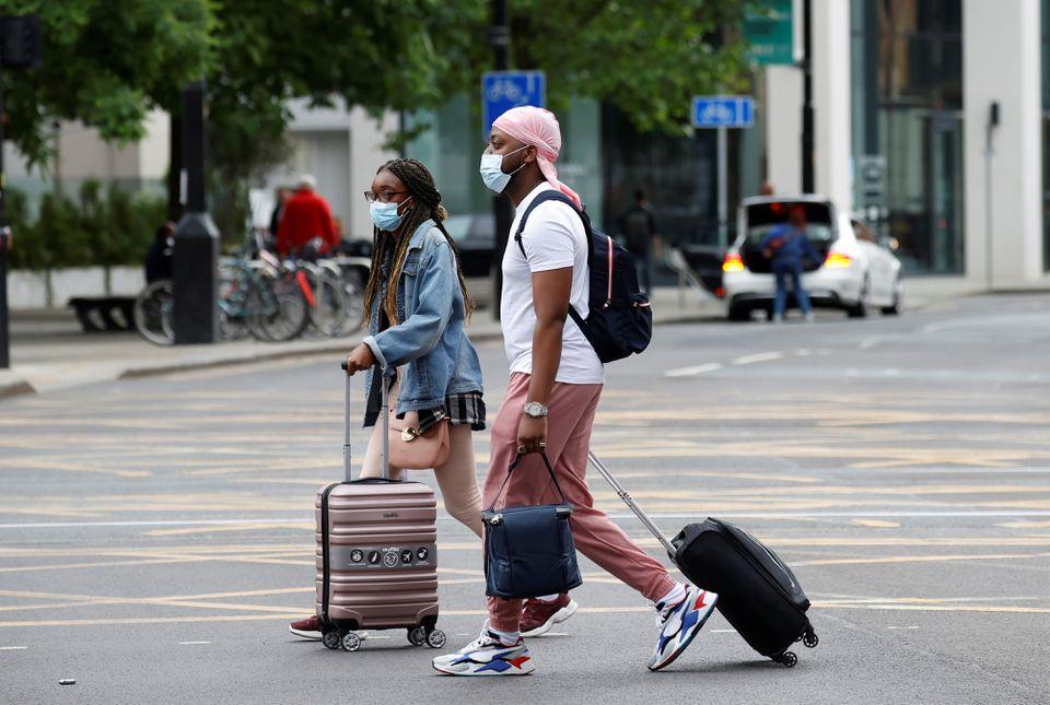 People wear protective masks as they walk with suitcases through the city centre, amid the outbreak of the coronavirus disease (COVID-19) in Manchester, Britain, June 21, 2021. - Avaz