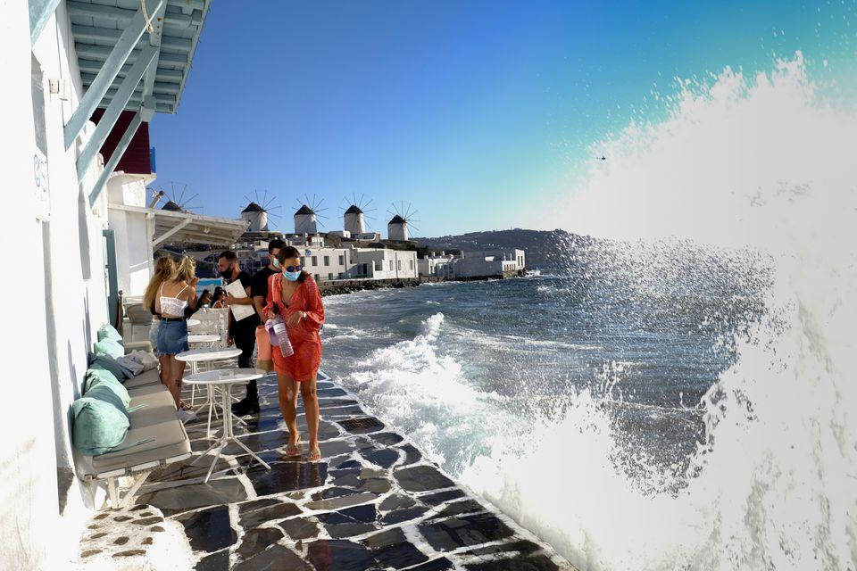 A woman wearing a protective face mask reacts as a wave crashes on a pier in Little Venice on the island of Mykonos, Greece, August 22, 2020. - Avaz