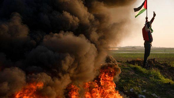 Palestinians burn tires and wave the national flag during a protest against Israeli military raid in the West Bank city of Jenin, along the border fence with Israel, in east of Gaza City - Avaz