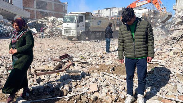 Taha Erdem, 17, right, his mother Zeliha Erdem, left, and father Ali Erdem stand next to the debris from a building where Tahan was trapped after the earthquake - Avaz