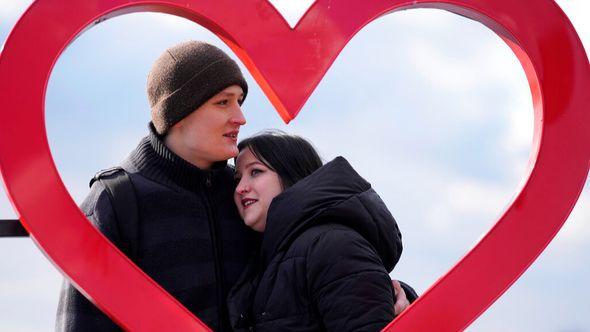 Mariia Vyhivska, from Ukraine, left, and Iurii Kurochkin, from Russia, pose with a heart-shaped sign on the banks of the Ada Ciganlija Lake, in Belgrade, Serbia - Avaz